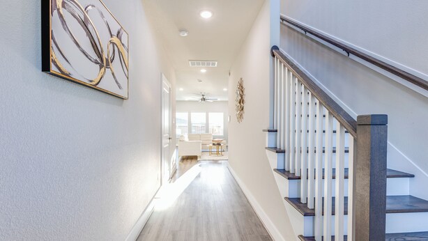 Ein Flur mit Treppe, Holzboden und Deckenventilator.