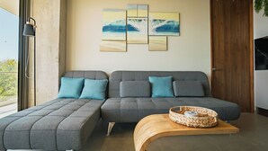 Ein modernes Wohnzimmer mit einem grauen Ecksofa, einem Holztisch und einem an der Wand befestigten Kunstwerk.