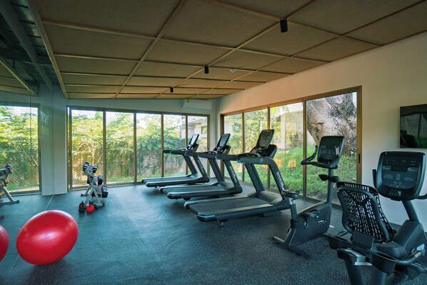 Un gimnasio con cintas de correr, pelotas de ejercicio y mancuernas.