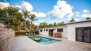 A modern house with a swimming pool, a patio area, and a small bar. - Villa Dubai by Glam Homes (Ojus)