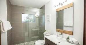 Een moderne badkamer met een douchecabine van glas, een wit wastafelmeubel en een grote spiegel.