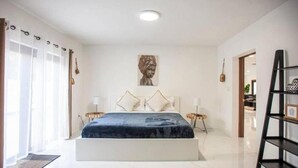 A bedroom with a bed, curtains, a painting, a bedside table, and a ladder. - Villa Dubai by Glam Homes (Ojus)