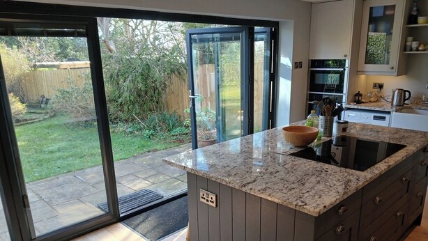 A modern kitchen with a granite countertop, a built-in oven, and a large window overlooking a garden. - Spacious 3BR Home with Garden and Parking (Southampton)