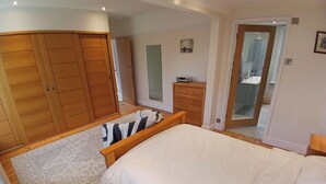 A bedroom with a bed, a wooden wardrobe, a dresser, and a mirror. - Spacious 3BR Home with Garden and Parking (Southampton)