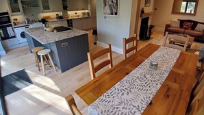 A modern kitchen with a central island, wooden dining table, and a living area with a sofa. - Spacious 3BR Home with Garden and Parking (Southampton)