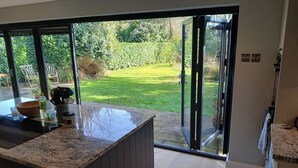 A kitchen with a large island, a sliding glass door leading to a garden, and a view of the outdoors. - Spacious 3BR Home with Garden and Parking (Southampton)