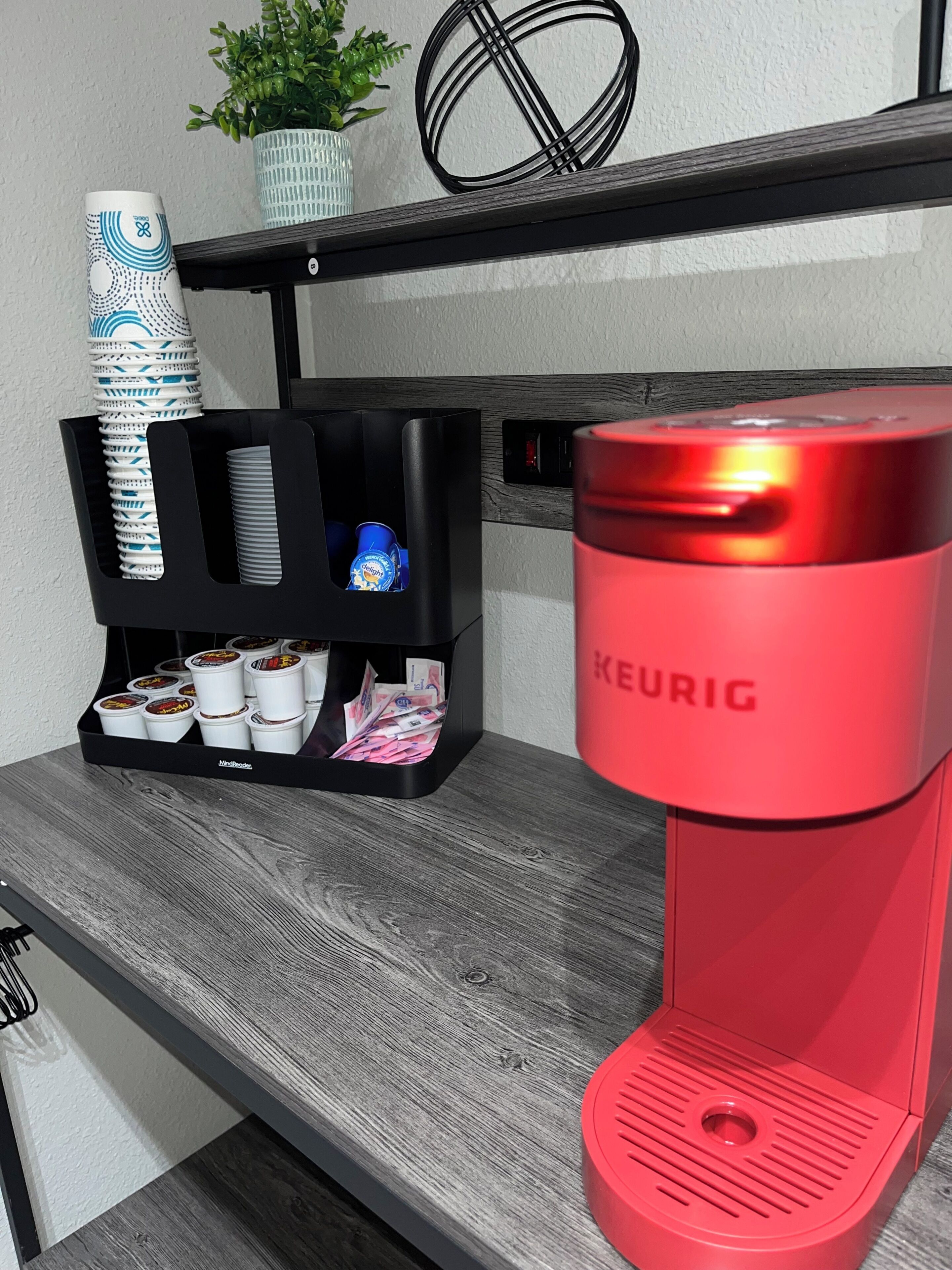 Een koffieapparaat met een rode basis en een zwarte koffieuitgifte.