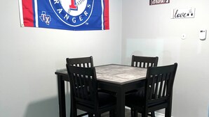 A dining area with a table and four chairs, a Texas Rangers flag on the wall, and three signs with words 'eat,' 'drink,' and 'love.' - Cozy & Comfortable in walking distance to AT&T, near Sixflags (Arlington)