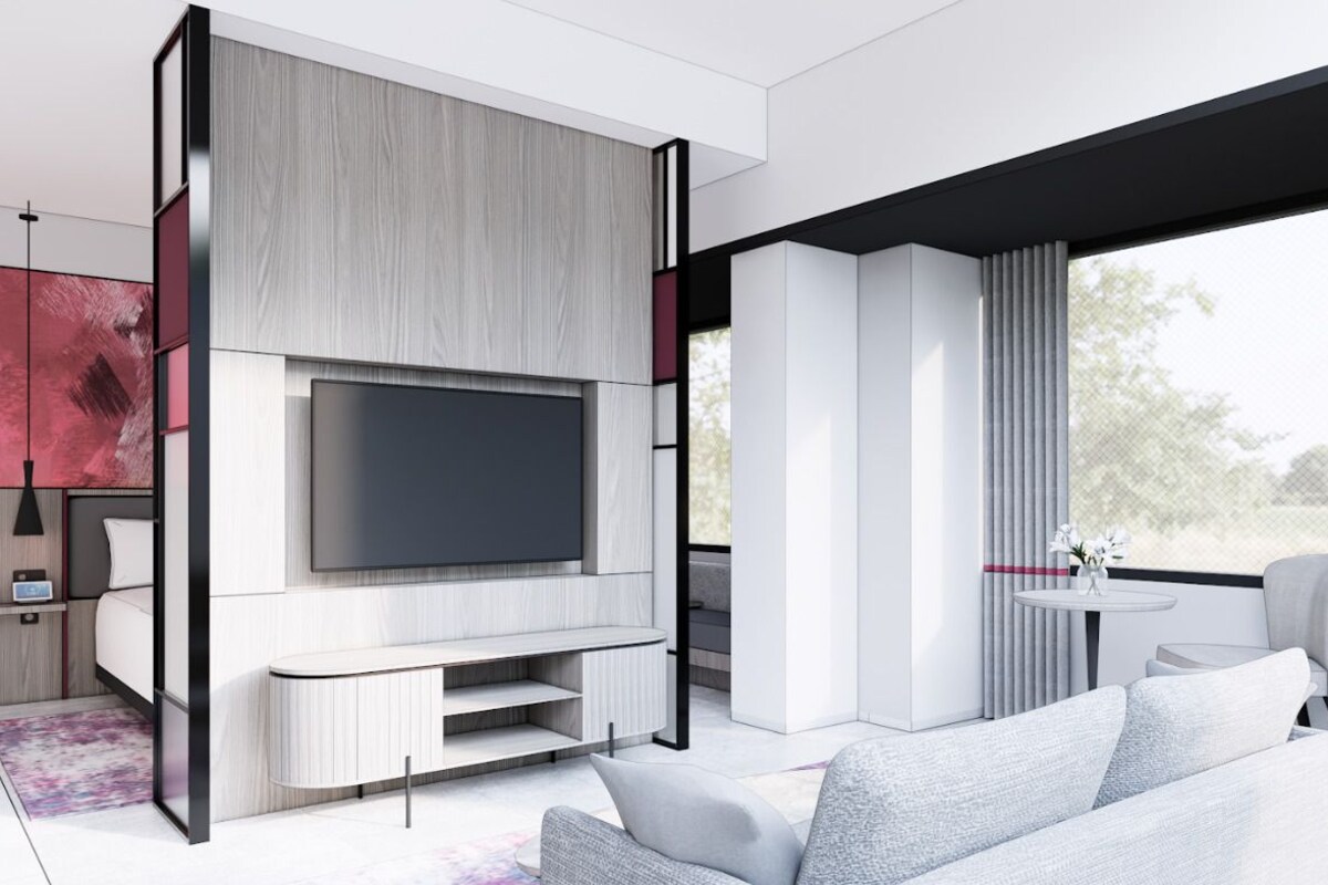 A modern living room with a flat-screen TV, a grey sofa, and a dining area with a table and chairs.