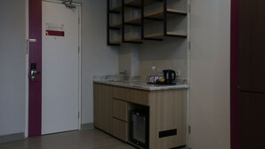 Una cocina compacta con refrigerador integrado, cafetera y microondas.