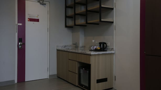 A compact kitchen with a built-in refrigerator, a coffee maker, and a microwave. - Fave+ Hotel Lampung (Bandar Lampung)