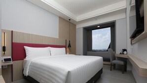 A modern hotel room with a large bed, a desk, a chair, a TV, and a window with a city view. - Fave+ Hotel Lampung (Bandar Lampung)