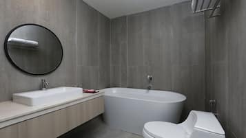 A modern bathroom with a freestanding bathtub, a toilet, and a round mirror.
