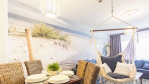 Een strandlounge met rieten meubels, een hangstoel en uitzicht op het strand.