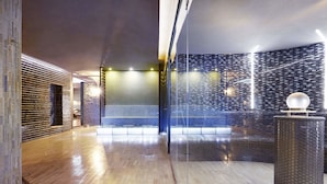 Een modern interieur met een houten vloer, een glazen scheidingswand en een behang met een patroon.