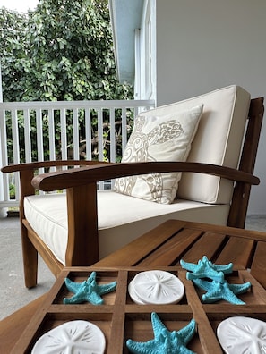A wooden bench with a cushioned seat and backrest, a white railing, and a table with starfish-shaped decorations.