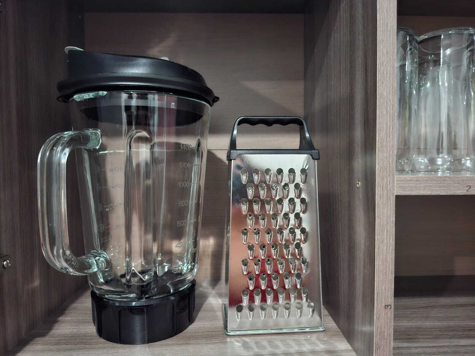 Una cocina con una licuadora y un rallador sobre una repisa de madera.