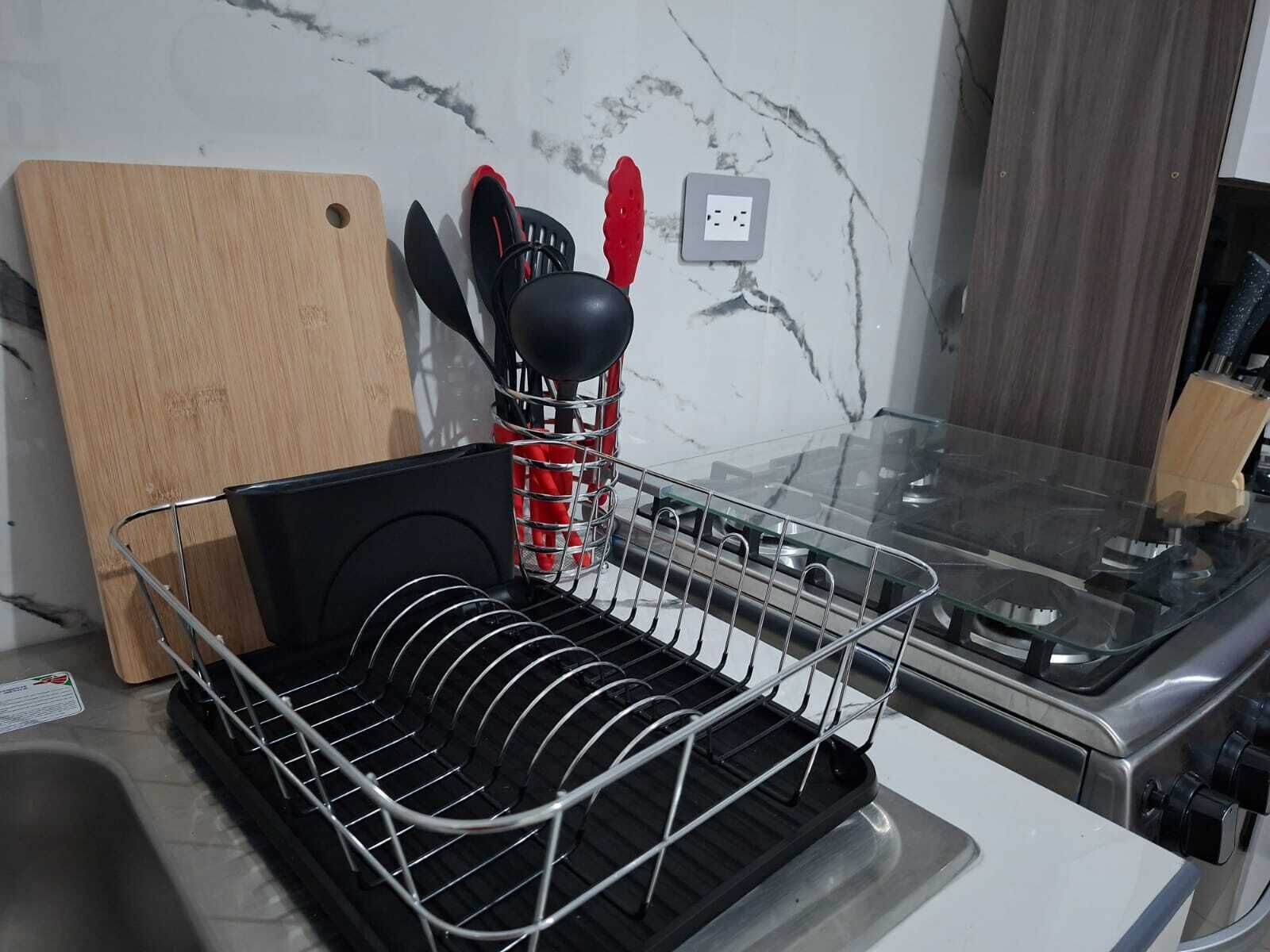 Uma cozinha com escorredor de louça, tábua de corte e fogão.