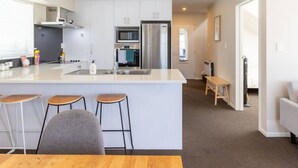 Cocina moderna con una isla central, taburetes de bar y una mesa de comedor.