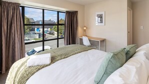 Habitación de hotel con una cama grande, un escritorio, una silla y una ventana con cortinas.