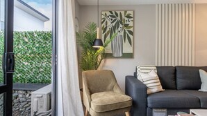 Ein Wohnzimmer mit Schlafsofa, Sessel, Lampe und Pflanze.