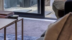 Ein Zimmer mit einer Schiebetür und Zugang zu einer Terrasse, einem weißen Plastikstuhl und einem kleinen Tisch mit Büchern.
