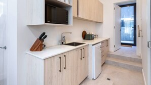 A modern kitchen with white cabinets, a sink, a microwave, and a toaster. - Hotel Comfort | Ground Floor, City Apartment (Christchurch)