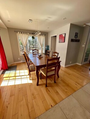 Un comedor con mesa y sillas de madera, una ventana con cortinas, un dispensador de agua y un cartel de Route 66 en la pared.