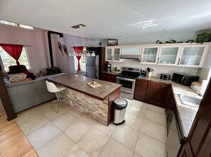 Una cocina moderna con una isla central, electrodomésticos de acero inoxidable y vistas al exterior.