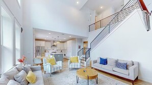 A spacious living area with a sofa, armchairs, a coffee table, and a staircase. - Perdido Bayside Retreat Near Beach! Pool, Dock, Pickleball (Pensacola)