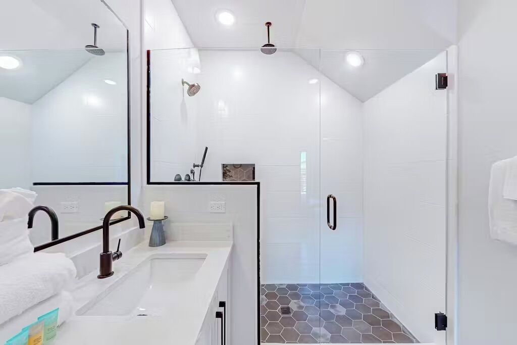 Un baño moderno con cabina de ducha de vidrio, lavabo blanco y espejo.