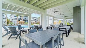 An outdoor patio area with tables and chairs, a pool, and a view of neighboring houses. - Perdido Bayside Retreat Near Beach! Pool, Dock, Pickleball (Pensacola)