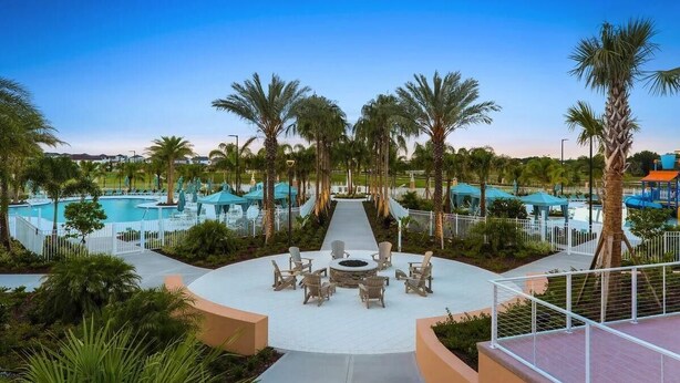 A pool area with lounge chairs and a fire pit, surrounded by palm trees and umbrellas. - 6BR/4.5BA Luxury Disney Decor w/ Pvt Pool & Resort (Kissimmee)