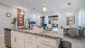 A modern kitchen with granite countertops, gold handles, and pendant lighting. - 6BR/4.5BA Luxury Disney Decor w/ Pvt Pool & Resort (Kissimmee)