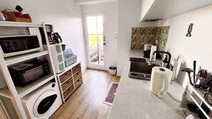 Eine kleine Küche mit Mikrowelle, Kaffeemaschine und Spüle.