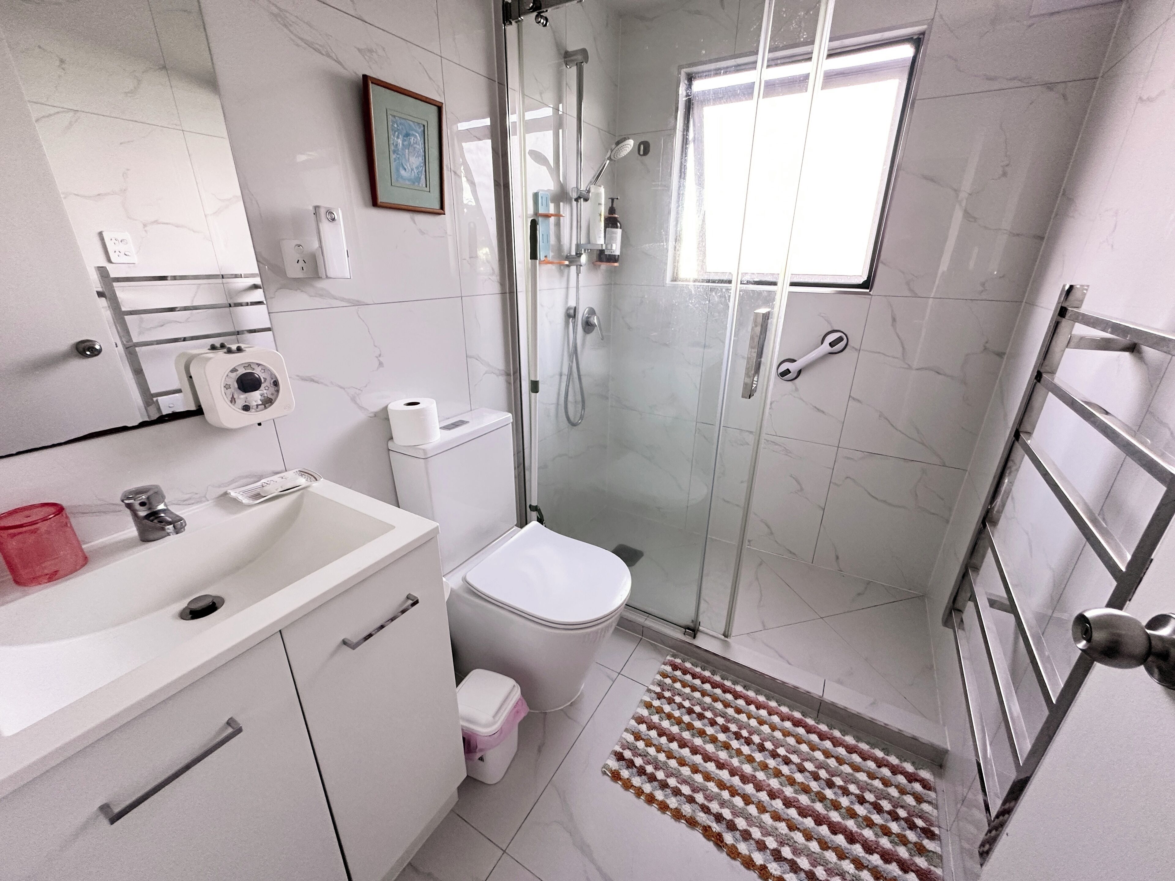 Ein Badezimmer mit Toilette, Waschbecken, Dusche und einem kleinen Fenster.