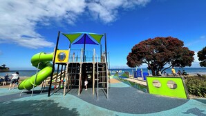 Ein Spielplatz mit Rutsche, Klettergeräten und einem schattigen Bereich.