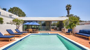 A swimming pool with lounge chairs and a glass-enclosed patio area. - New! La Jolla Shores 2BD with Pool- Walk to Beach! (La Jolla)