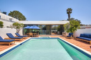 A swimming pool with lounge chairs and a glass-enclosed patio area. - New! La Jolla Shores 2BD with Pool- Walk to Beach! (La Jolla)