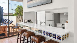 A modern kitchen with a bar area, white cabinets, and a tiled backsplash. - New! La Jolla Shores 2BD with Pool- Walk to Beach! (La Jolla)