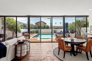 Un patio con piscina, mobiliario exterior y vistas del vecindario.