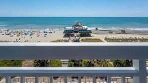 Uitzicht op een strand met een redershutje, parasols en een gebouw met een blauw dak.