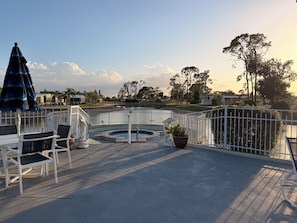 A poolside area with a hot tub, lounge chairs, and a view of the surrounding landscape. -  LIVE THE FLORIDA LIFESTYLE – 2 BedBath in Beautiful Gated Golf Community (North Fort Myers)