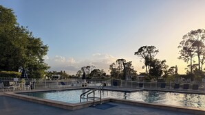 Ein Schwimmbecken mit Liegestühlen und einem Zaun.