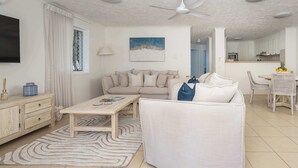 Ein modernes Wohnzimmer mit Sofa, Couchtisch und einem Essbereich mit Stühlen und Tisch.