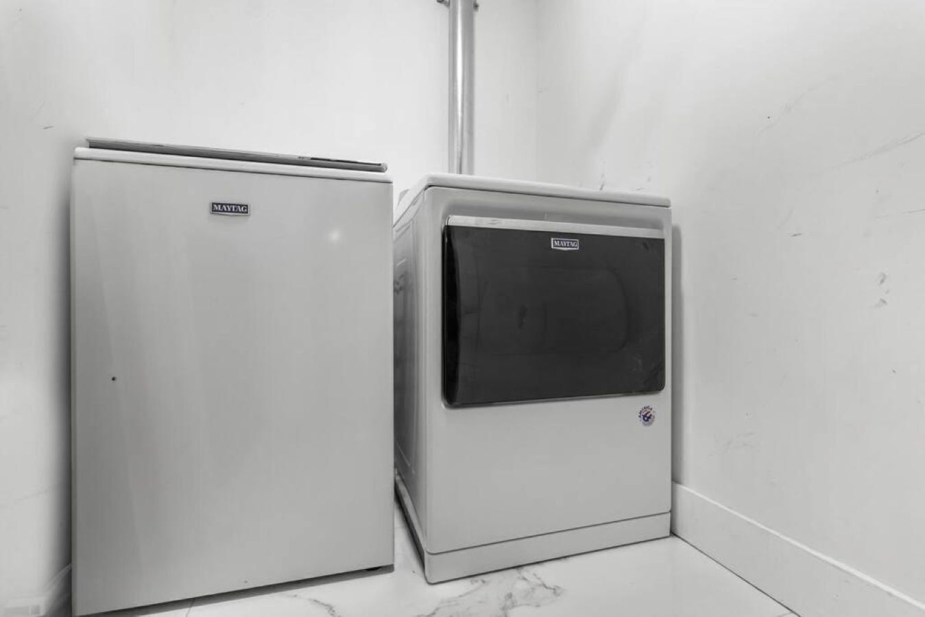 Two Maytag appliances, one with a front door and one with a window, in a corner with a tiled floor.