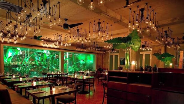 A restaurant with multiple dining tables, hanging light fixtures, and a large aquarium. - Elevate Your Stay! Prime 2 Beds Home w Ocean View! (San Juan)