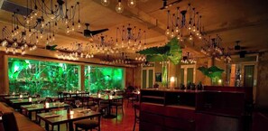 Een restaurant met verschillende eettafels, hangende lampen en een groot aquarium.