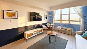 A modern living room with a sofa, a coffee table, a TV, and artwork on the wall. - Elevate Your Stay! Prime 2 Beds Home w Ocean View! (San Juan)