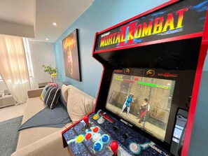 Een speelhal met Mortal Kombat II, een beige bank en een schilderij aan de muur.